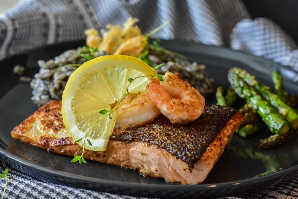 Raw salmon fillets brushed with lemon garlic marinade on a parchment-lined baking sheet.
