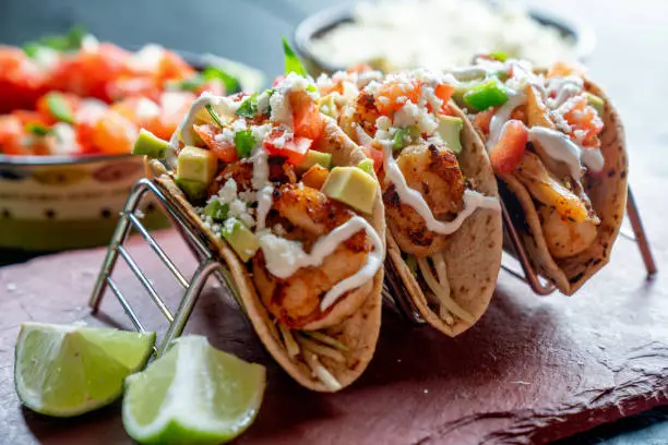 Overhead view of fish tacos with cabbage slaw, avocado and vegetables