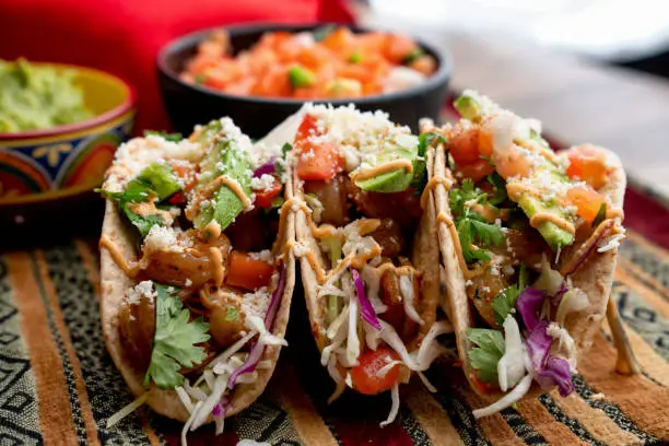 Overhead view of fish tacos with cabbage slaw, avocado, and creamy chipotle sauce, served with limes